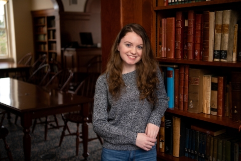 Giuliana Ferrara '22 smiles in front of a bookshelf.