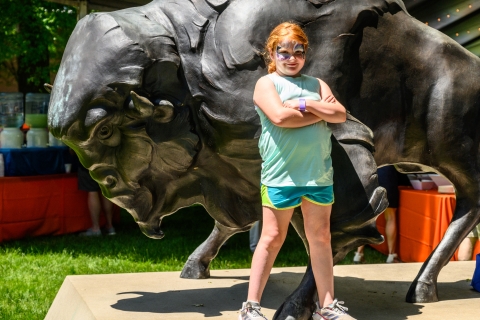 A child standing in front of the bison statue