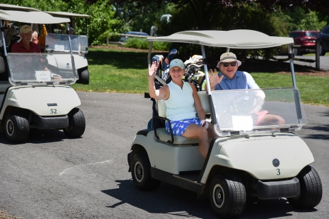 Couple in golf cart waving