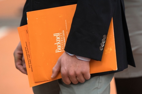 A close up image of a student holding orange folders