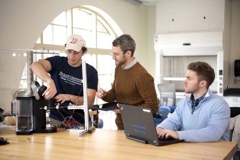 Two senior design project students work with Professor Ben Wheatley on their Keurig project.