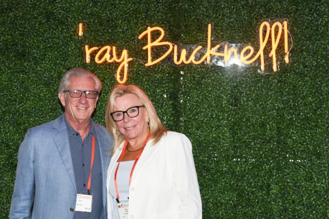 Alumni pose in front of a neon "'ray Bucknell" sign.