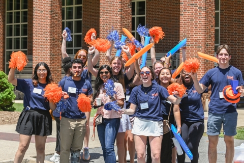 A group of students wave pom poms and cheer.