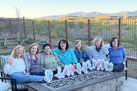 Members of the Class of 1977 sit at a table together with locked arms and smile