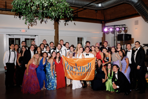 Group photo at a wedding holding a Bucknell flag