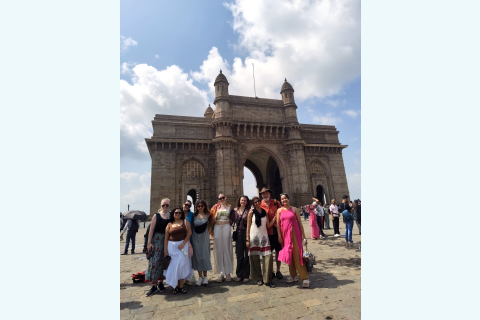 Nine Bucknell students and faculty members pose together in front of the Gateway of India, a monumental stone arch in Mumbai.
