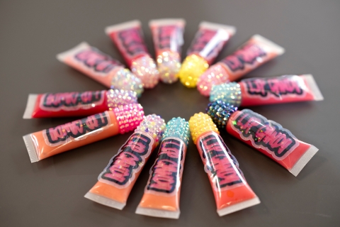Bejeweled tubes of Lyric's Lip Candy in pink, orange and red shades lie in a circle