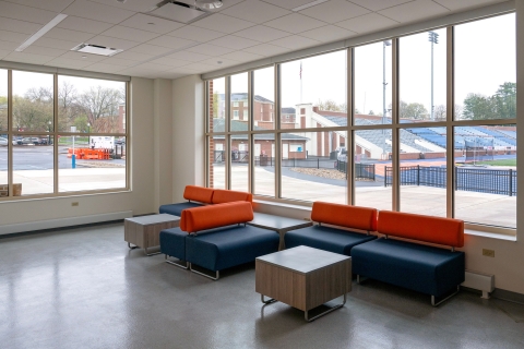 A lounge space feature blue and orange couches and a view of Christy Mathewson–Memorial Stadium