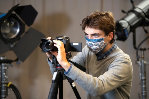 Student with camera in media studio
