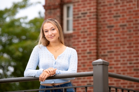 Sami Wurm ’22 stands behind a brick wall on campus