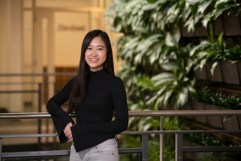 Wutt Kyi stands in front of a wall of plants.