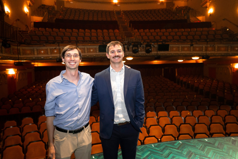 Professor Sam Gutekunst and Chris Kopac '25 stand together in a Broadway theatre with rows of empty seats behind them.