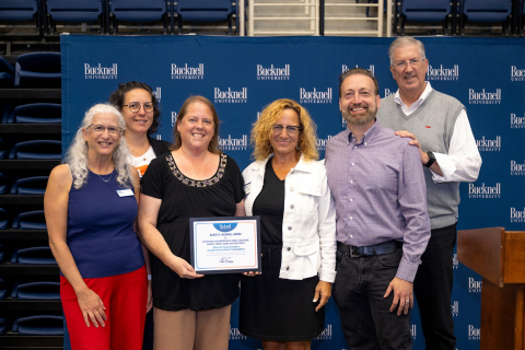 A group of six people stand together while receiving an award.