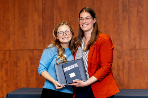 Claire Hayes smiles as she receives an award from Adrienne Jensen-Doray
