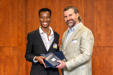 Thandeka Bango smiles as he accepts an award from Bill McCoy