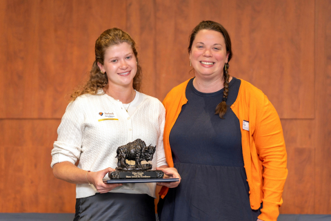 Eliza Morris ’26 smiles while holding a bison award with Erin Pascal.