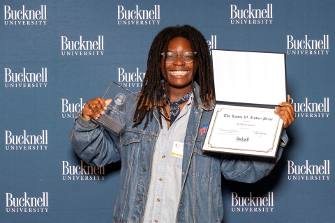 Da’Mirah Vinson '26 holds two awards, one in each hand, up and smiles.