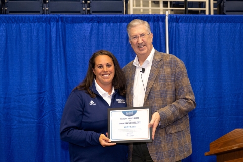 Kelly Cook stands with John Bravman as he hands her an award