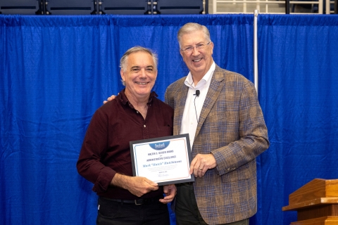 Mark "Hutch" Hutchinson stands with John Bravman and smiles and holds an award
