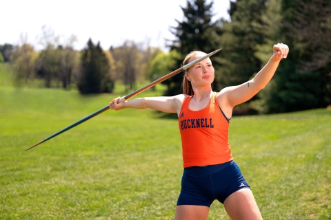 Madelyn Hudak wears her Bucknell track kit and runs as she's about to throw a javelin.