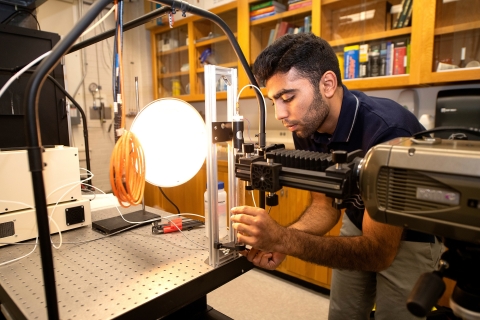Abdullah Nabi leans over a workbench in a mechanical engineering lab