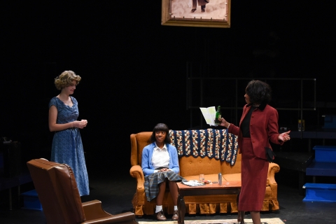 Three students acting on a stage. 