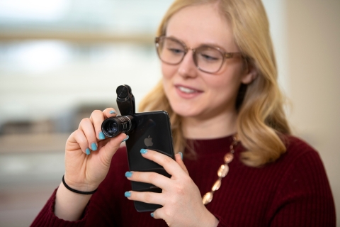 Rebecca Rosenberg attaches a camera lens to her iPhone.