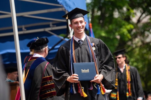 Student holding diploma on stage