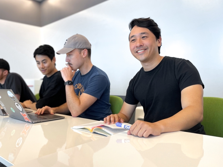 Alumni Brian Pei at his office sitting next to co-workers.