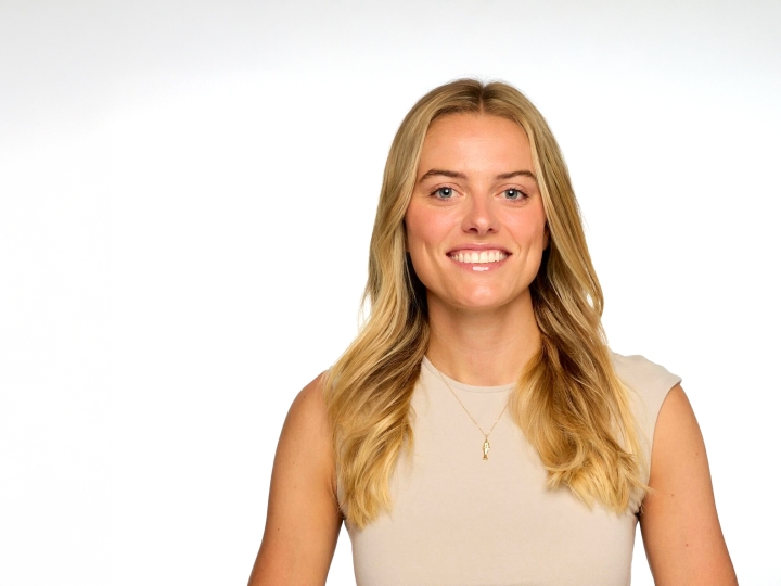 Cricket Treanor '18 smiles while wearing a beige sleeveless top against a white background.