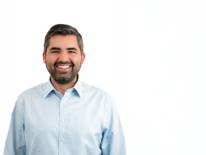 Michel Ajjan wears a white button-down collared shirt and smiles.