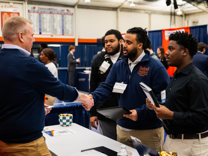 Students at a career fair shake hands with an employer