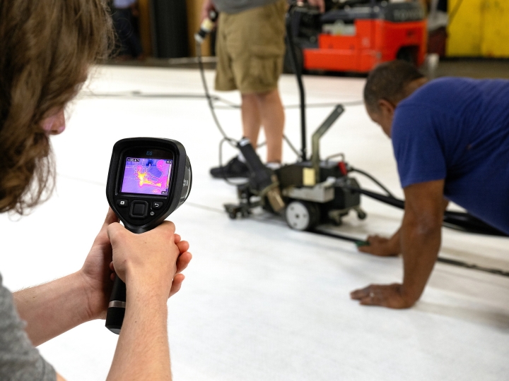 Close up of a student using an infrared camera to collect heat data from a mat welder