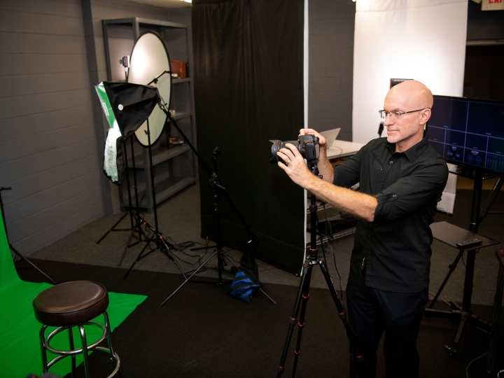 Mark Burke examines a camera while inside a studio.