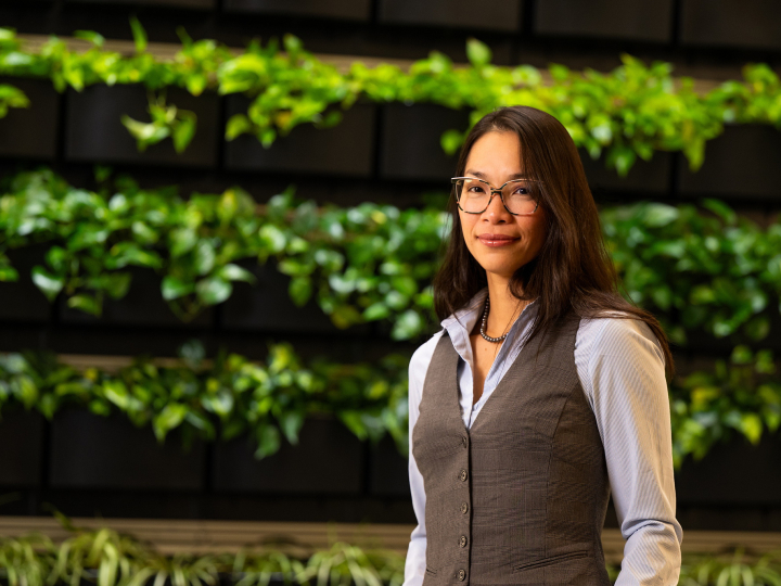 Christine Ngo stands in front of a green, leafy background.