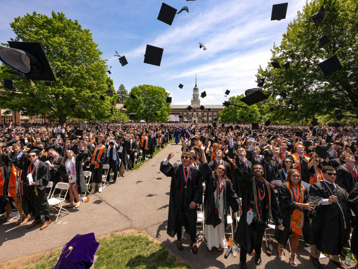 Graduates throw their caps into the air while standing outside
