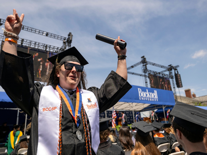 A graduate holds up his degree as he exits the Commencement stage at Bucknell's 2026 Commencement ceremony.