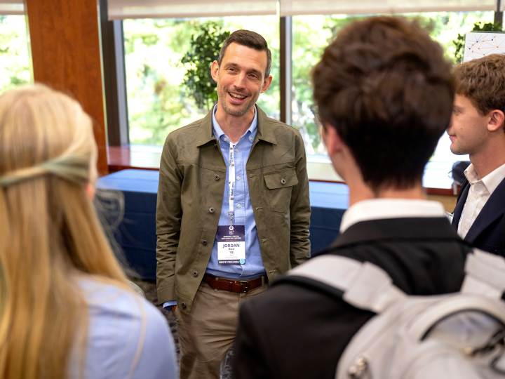 Jordan Rice smiles while talking with a small group of students gathered around him at EC⁴.