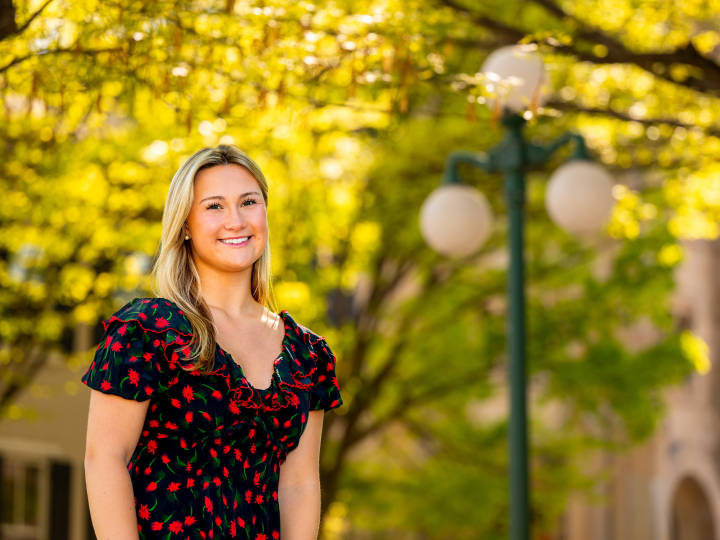 Margo Bigue smiles on campus with bright yellow foliage and a Lewisburg lightpost behind her.