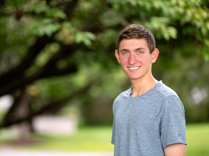 Abbott Spiller smiles; a tree and green grass are visible behind him.