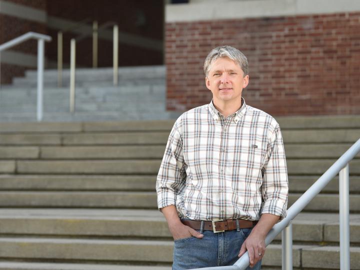 Professor Will Kerber poses on the steps of the Rooke Science Building