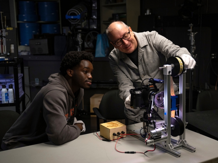 John Ogunwomoju '27 and Professor Eric Faden smile as they work using a film projector
