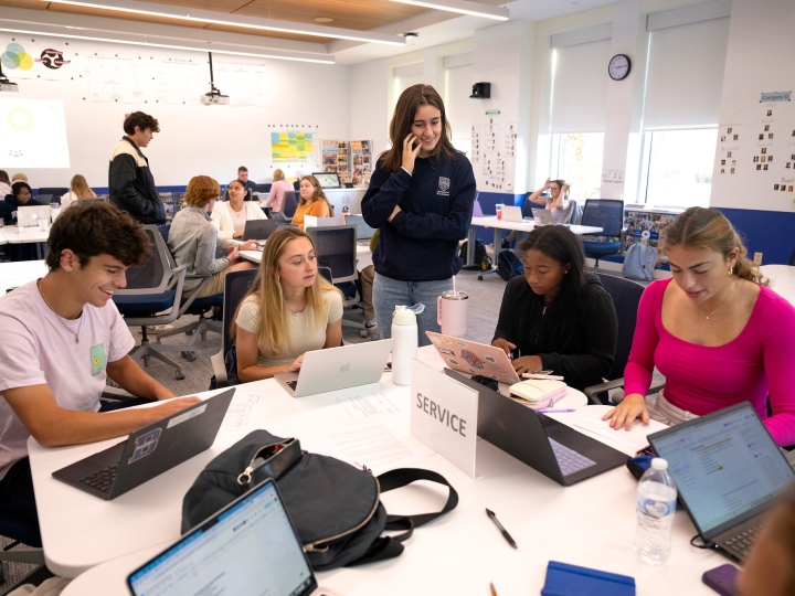 MGMT 101 students work together around a table.
