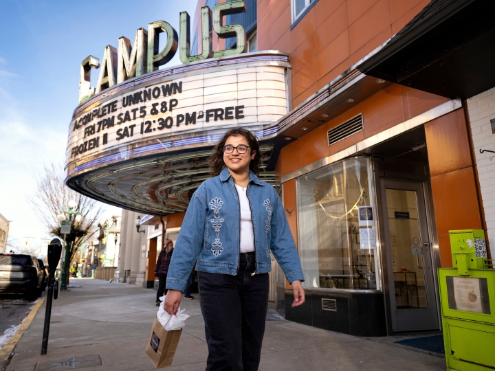 Waina Ali '26 walks down the sidewalk in downtown Lewisburg with the Campus Theatre marquee behind her.