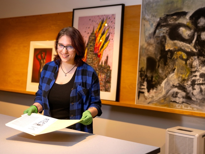 Hannah Kosko wears gloves as she holds a print in the Samek Art Museum.