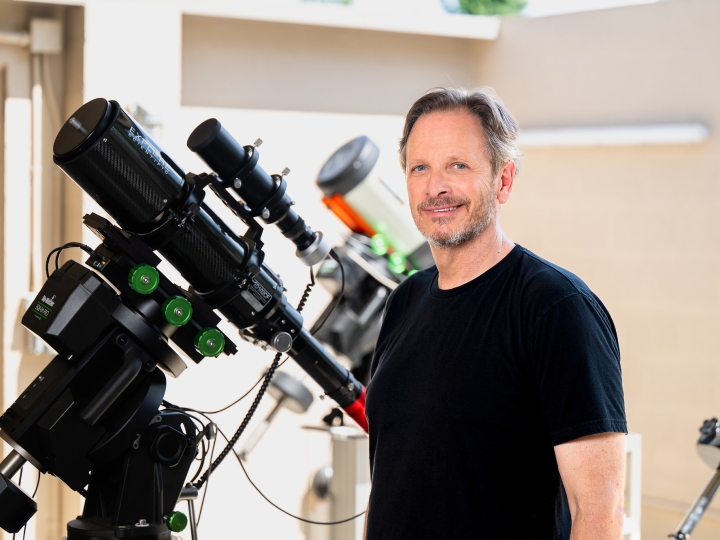 Jack Gallimore stands next to a telescope 