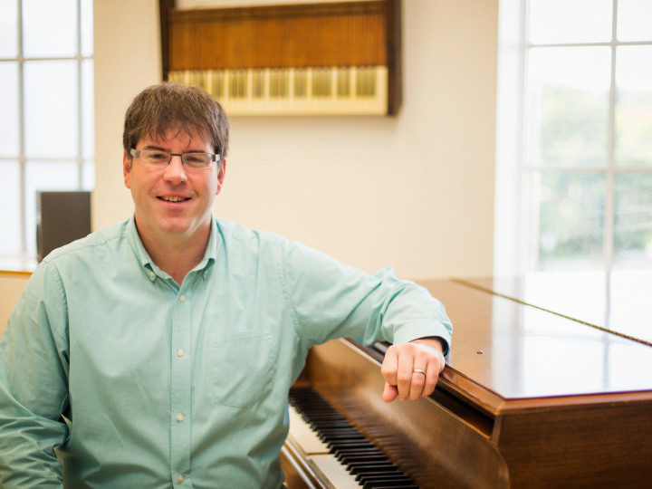 Ryan Malone sits with his elbow propped up on the edge of an organ.