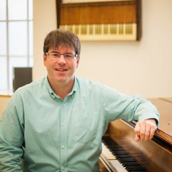 Ryan Malone sits with his elbow propped up on the edge of an organ.