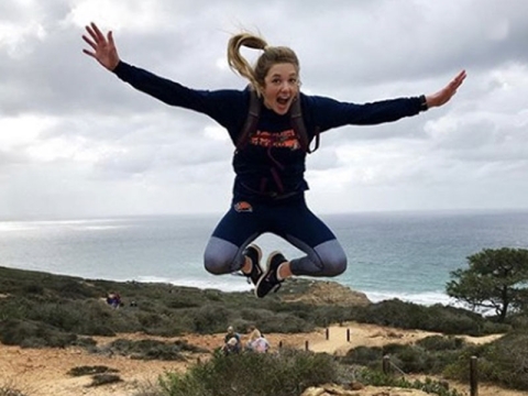 Student jumps in the air near the beach
