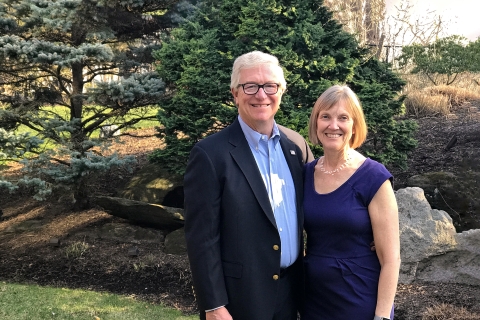 Steve Holmes and his wife, Bonnie Bencsko Holmes '79 pose outside in front of a pine tree